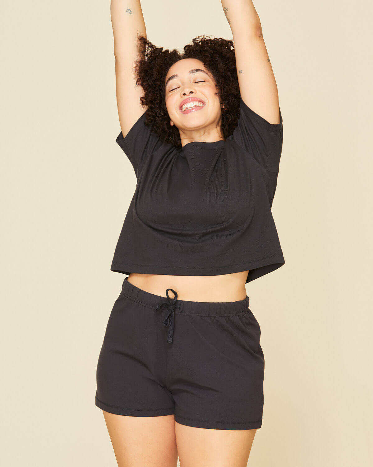 Woman wearing the boxy tee in graphite gray and the soft short in graphite gray color.