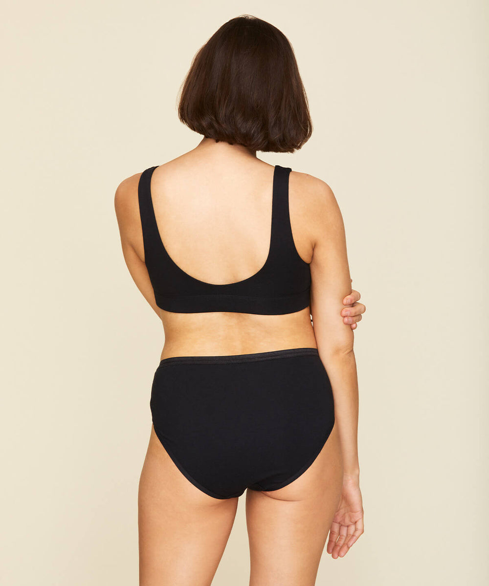 Woman wearing the mid rise brief in carbon black color.