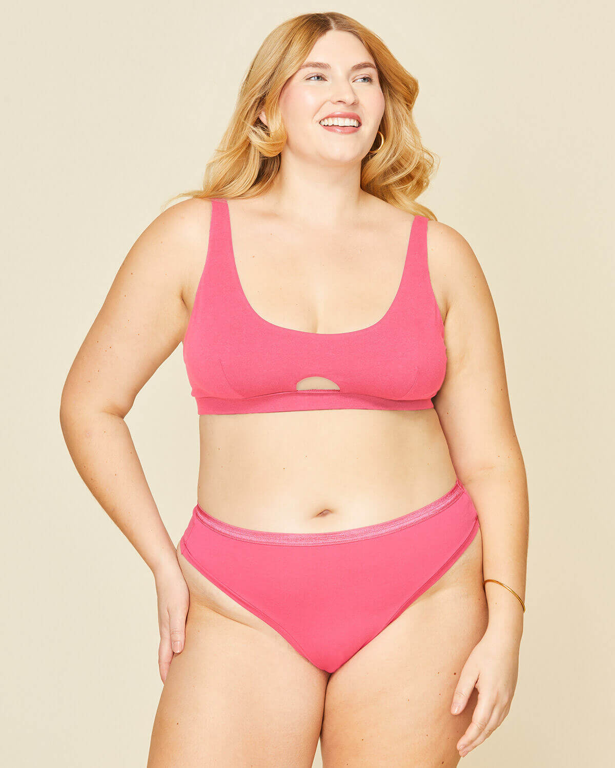 Woman wearing the mid rise thong in aurora pink and the keyhole soft bra in aurora pink color.