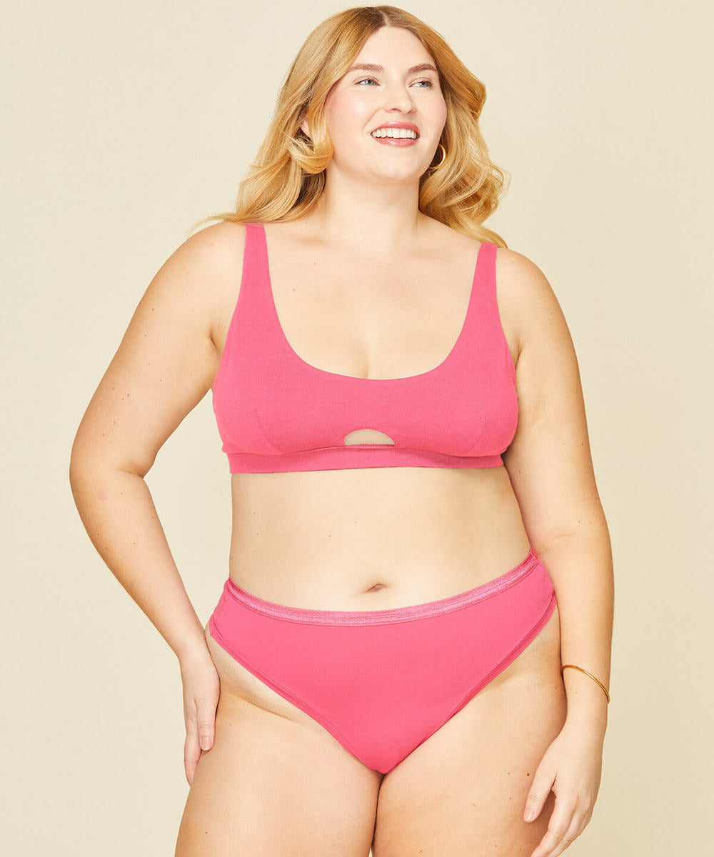 Woman wearing the mid rise thong in aurora pink and keyhole soft bra in aurora pink color.