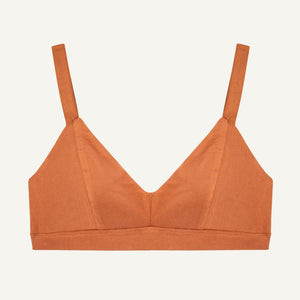 An organic cotton triangle soft bra in spice orange color with adjustable straps and a center seam.