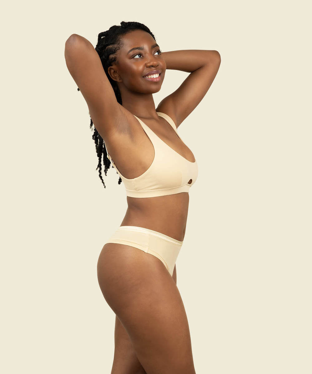 Woman wearing the mid rise thong in wheat and keyhole soft bra in wheat cream color.