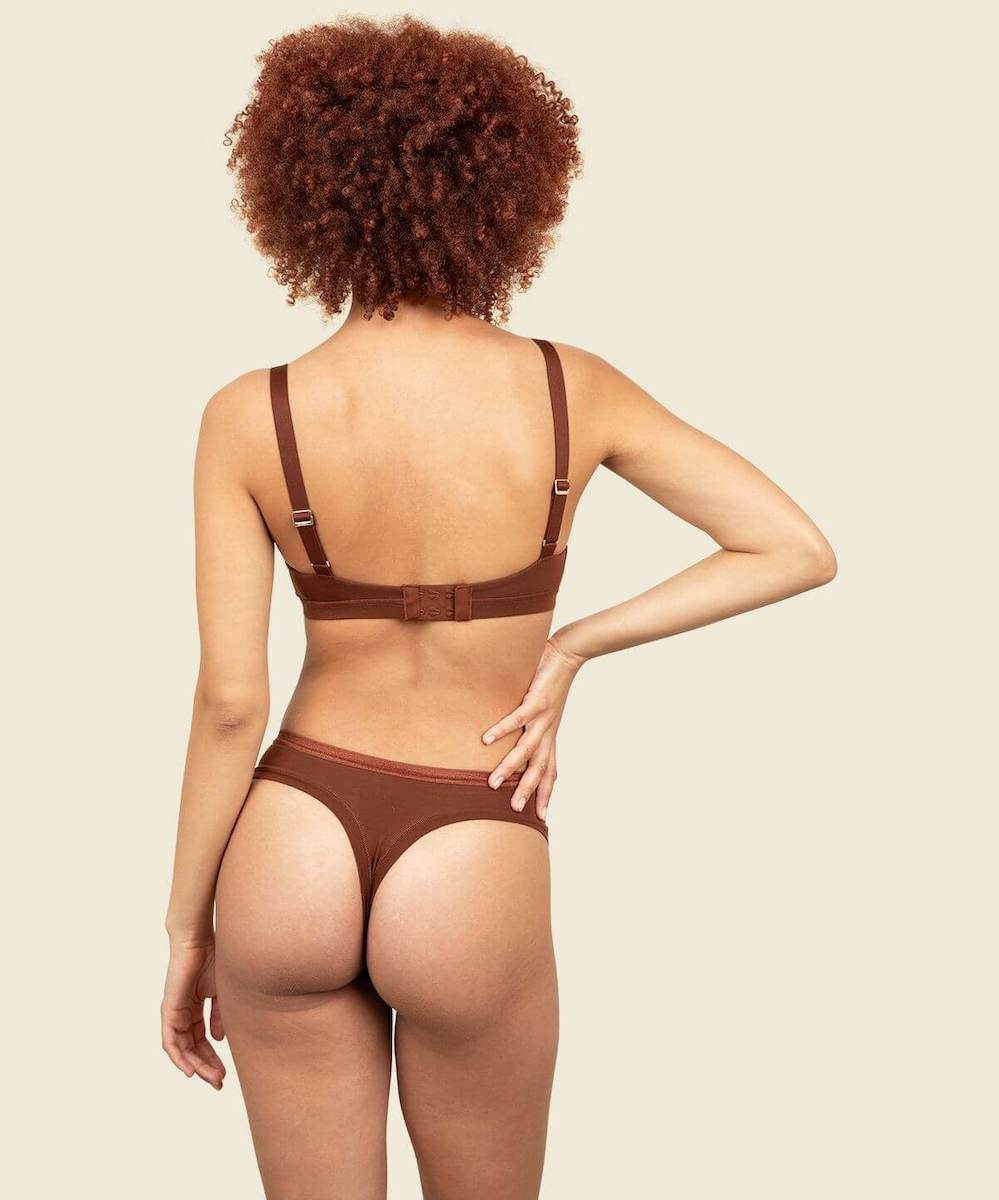 Woman in organic cotton mid-rise thong and triangle soft bra in cacao brown color.