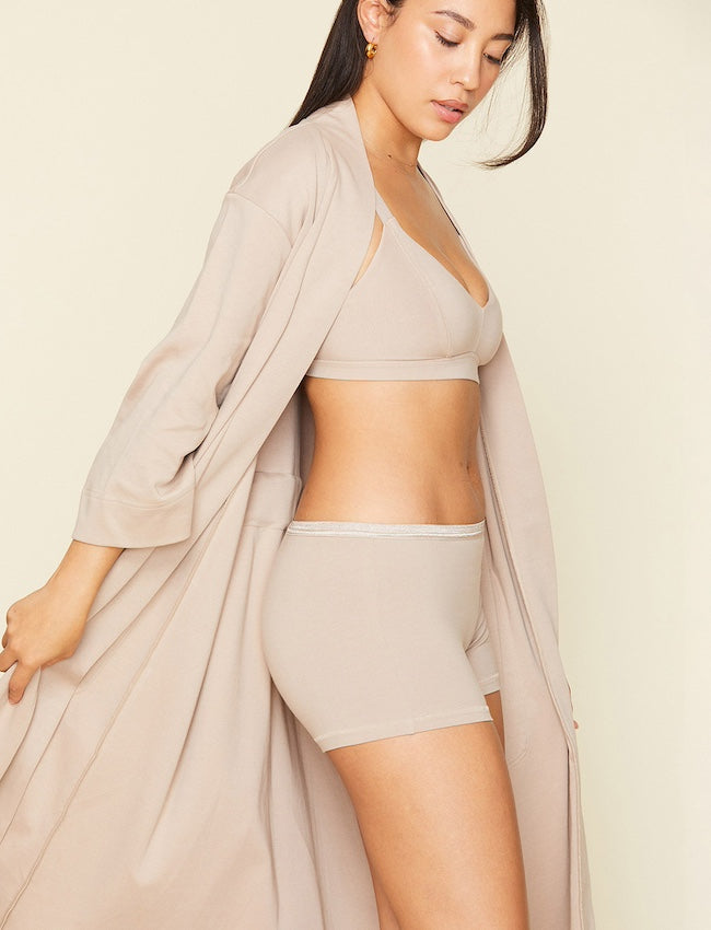 Woman wearing the organic cotton robe in stone beige color.