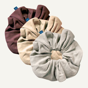 Three velvet scrunchies in brown, beige, and gray on a white background