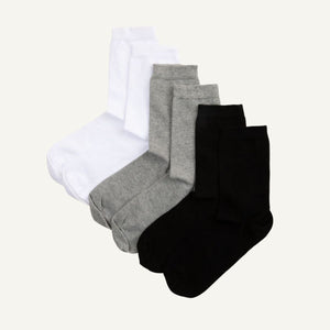 A set of three folded crew socks in white, grey, and black.