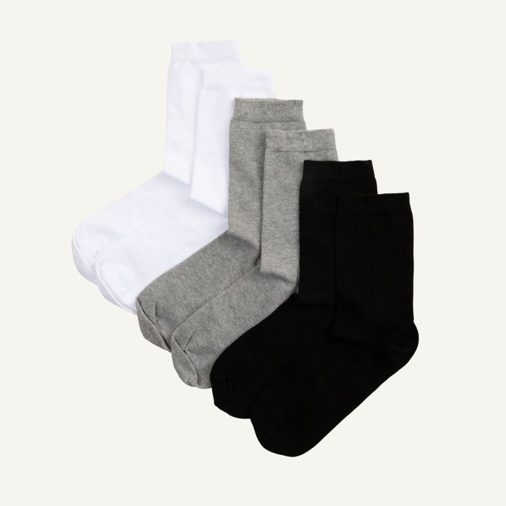 A set of three folded crew socks in white, grey, and black.