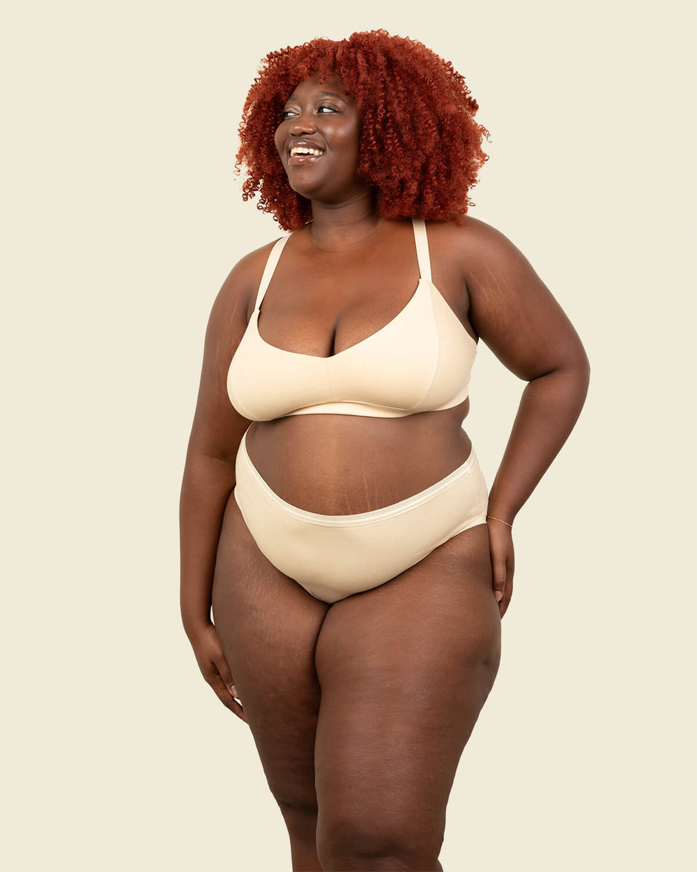 Woman wearing organic cotton high rise brief underwear and triangle soft bra in wheat beige color.