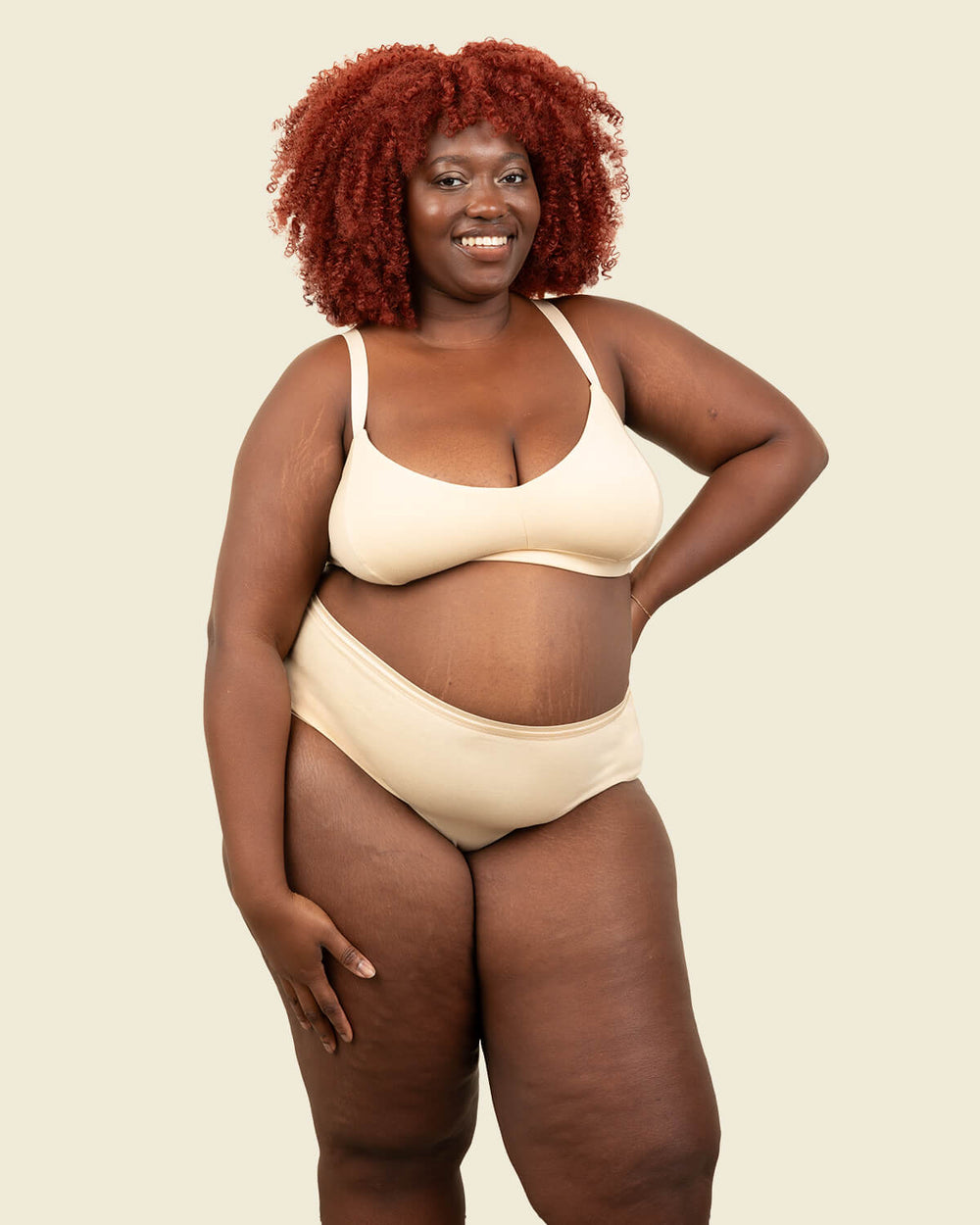 Woman in organic cotton mid rise brief underwear and triangle soft bra in wheat beige color.